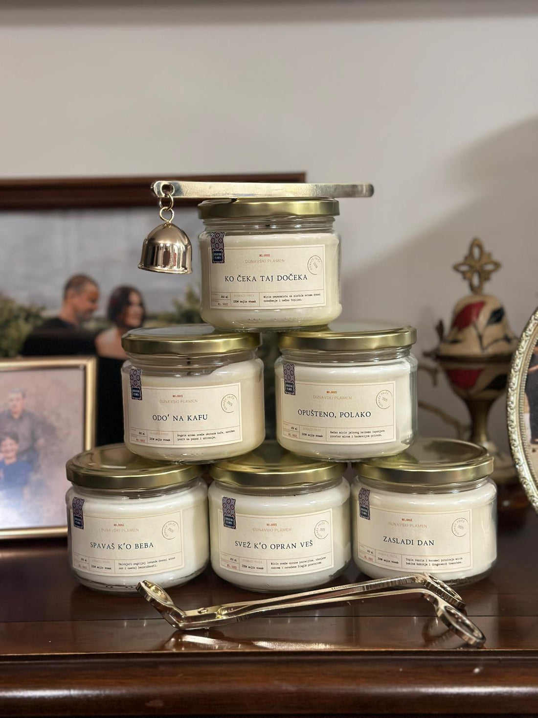 Sveće iz kolekcije Domaće Priče na stolu uz čipku, džezvu i papir sa starim izrekama — simbol tradicije i mirisa.