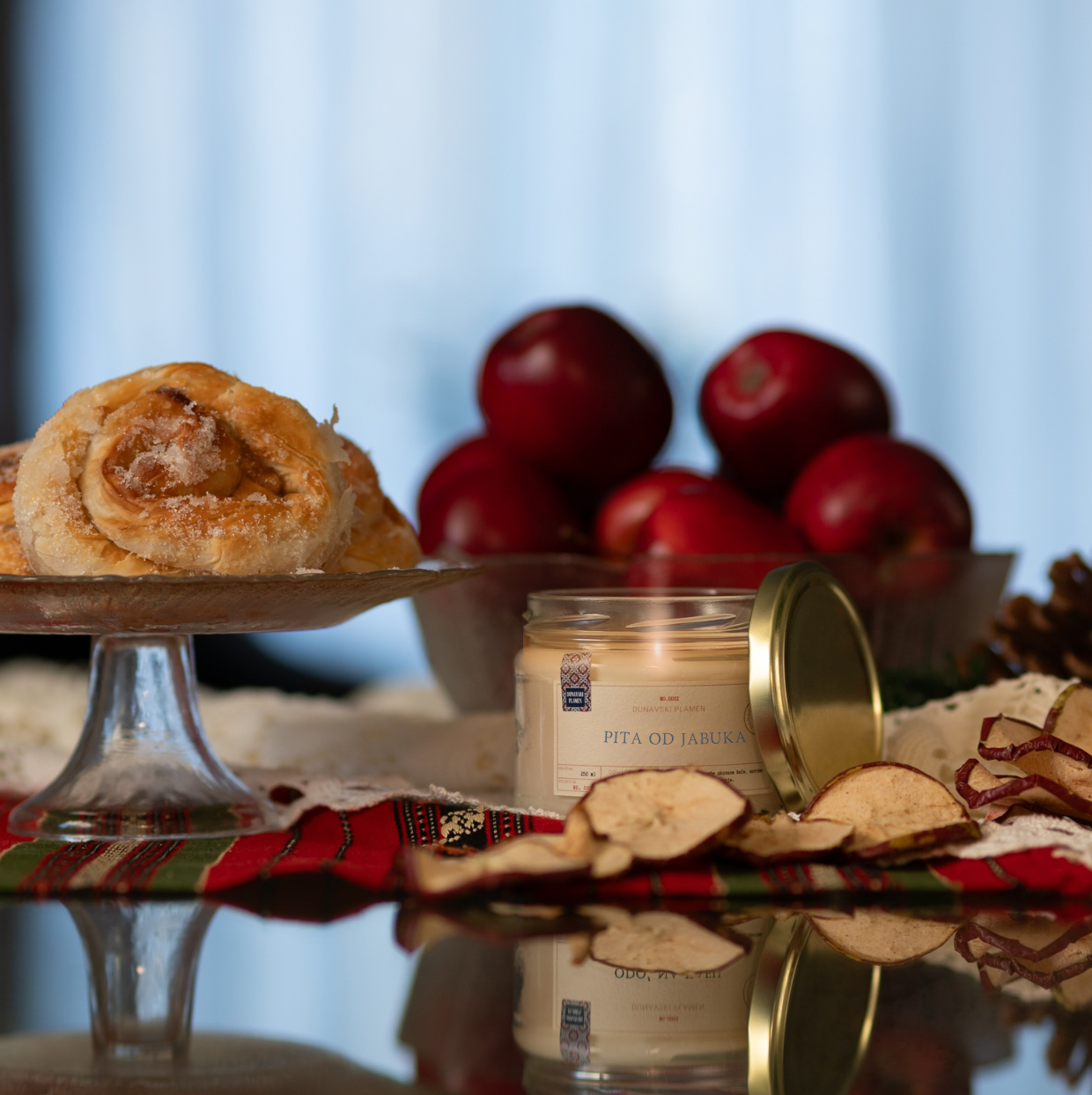 Mirisna sojina sveća Krempita iz kolekcije Ususkani Dani brenda Dunavski Plamen – ručno pravljena sveća sa slatkim mirisom vanile i kreme, inspirisana domaćim kolačem krempitom, uz praznični sto i božićnu dekoraciju.