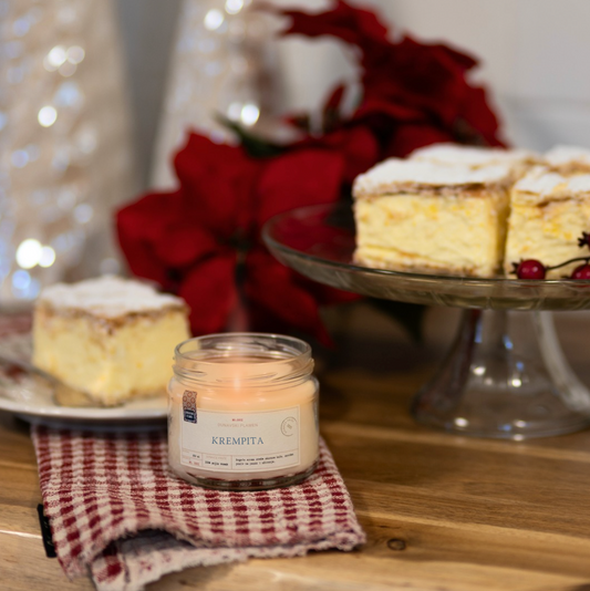 Mirisna sojina sveća Krempita iz kolekcije Ususkani Dani brenda Dunavski Plamen – ručno pravljena sveća sa slatkim mirisom vanile i kreme, inspirisana domaćim kolačem krempitom, uz praznični sto i božićnu dekoraciju.